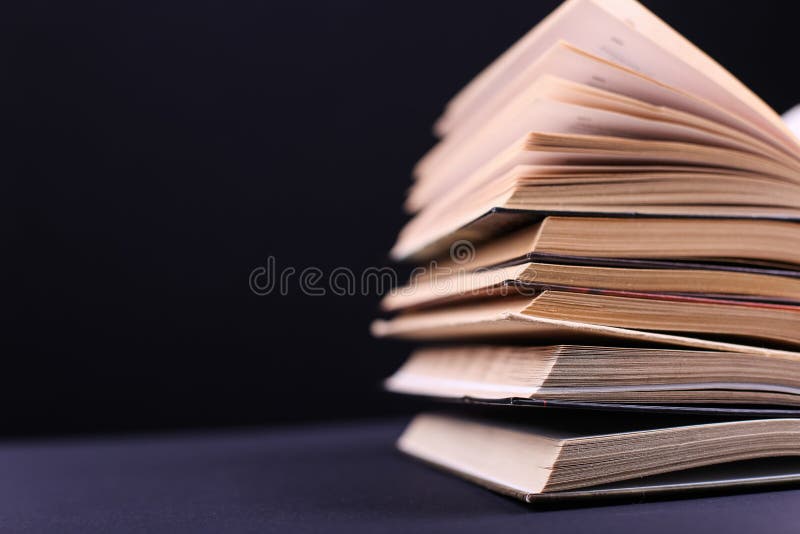 开放书在书桌上被堆积,在黑背景,孤立 困难的家庭作业在学校,知识山 库存图片 开放书在书桌上被堆积,在黑背景,孤立 困难的家庭作业在学校,知识山 库存图片